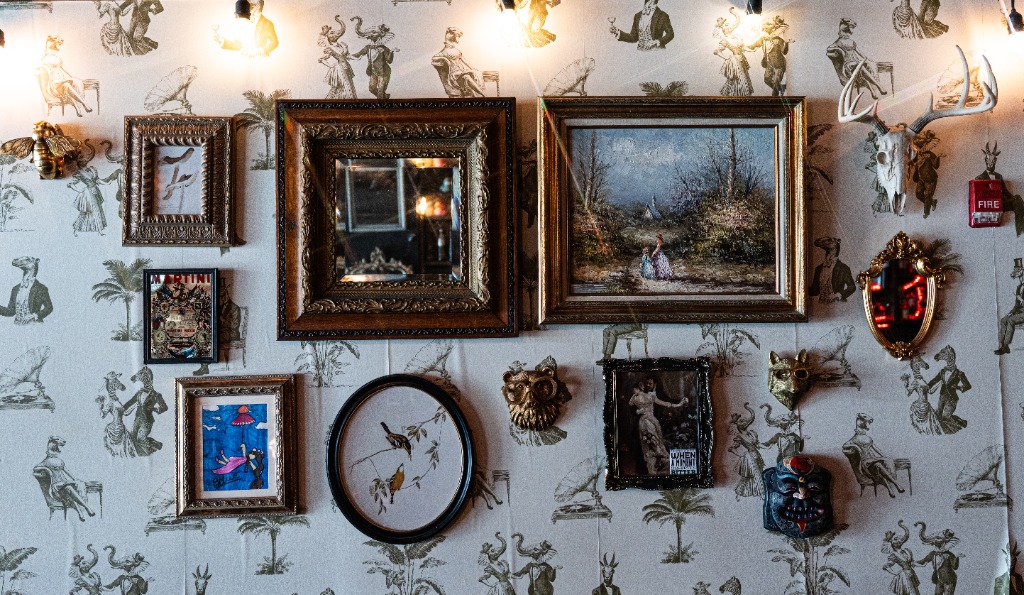 Vintage gallery wall featuring ornate framed art and speakeasy decor at Mackenzie's in Old Town Fairfax